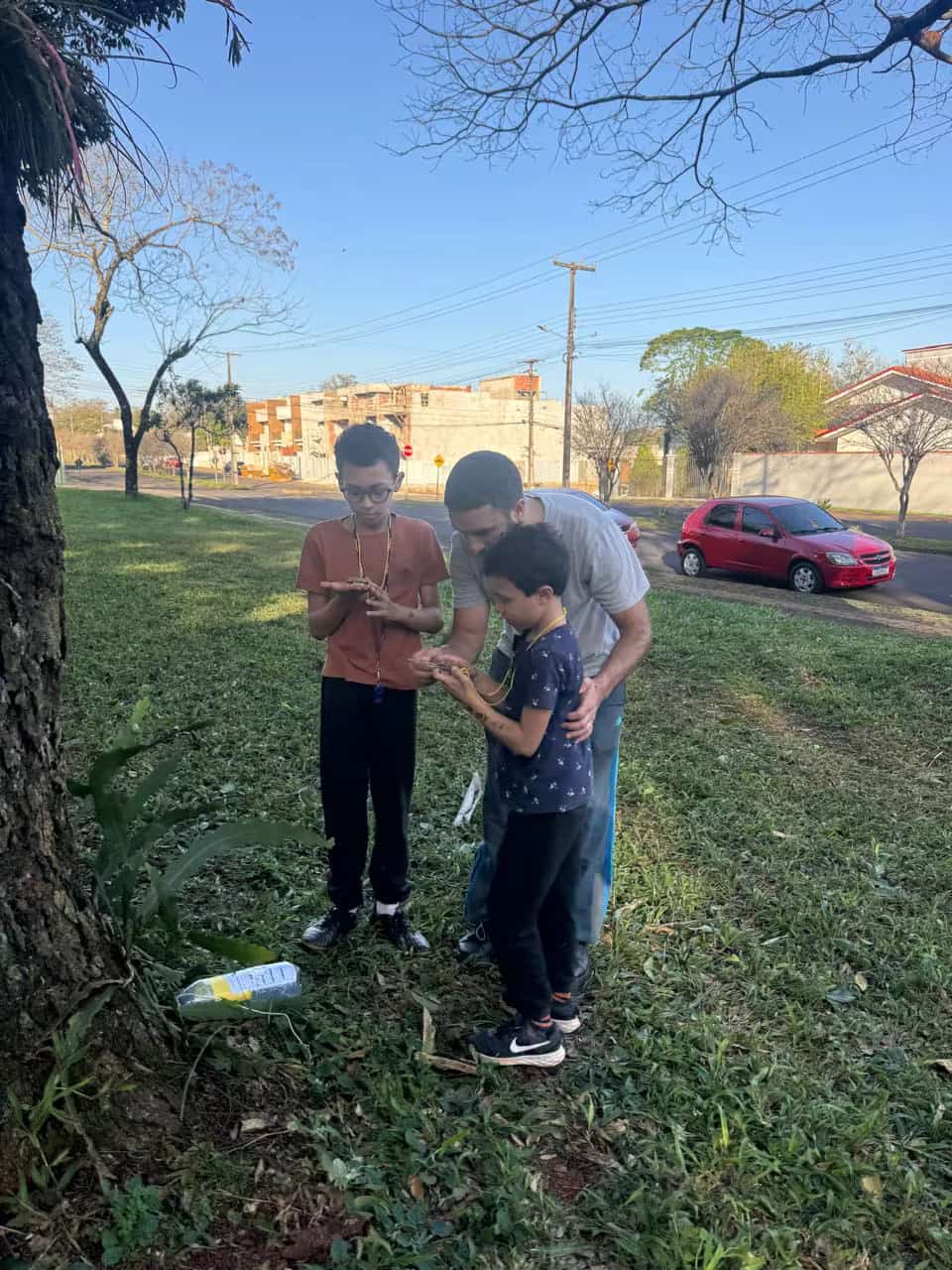 Homem acompanha dois meninos em uma atividade ao ar livre
