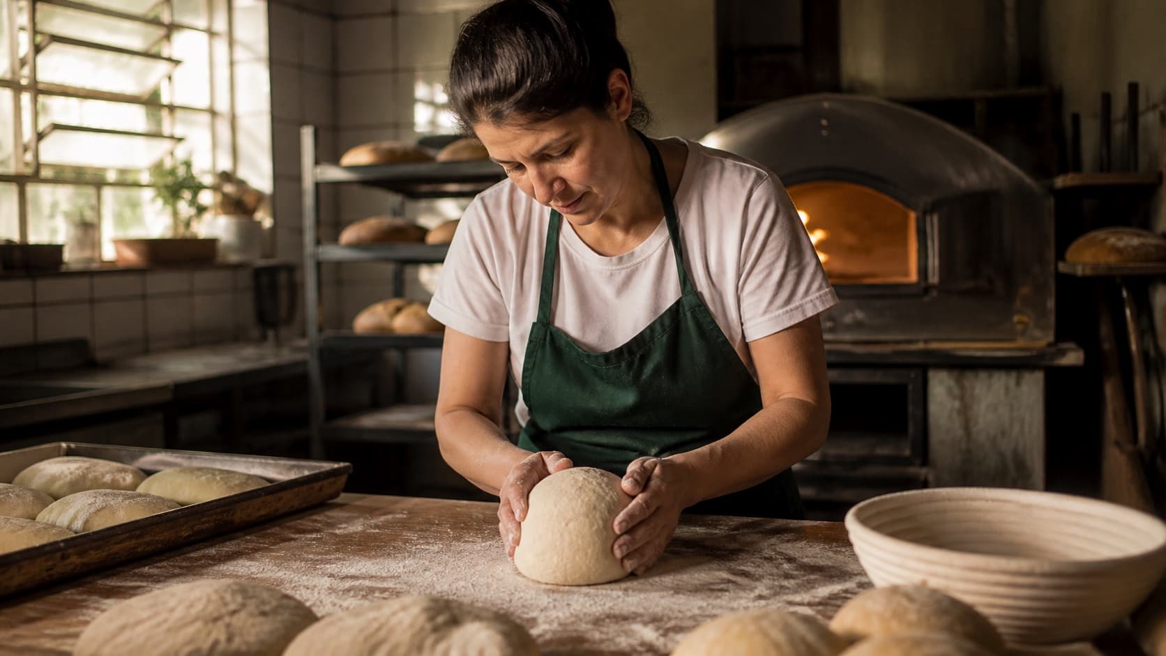 Padeira prepara pão com atenção em uma padaria de bairro
